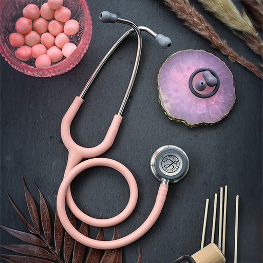 Satin Champagne Rose Tube 3M™ Littmann® Classic III Monitoring stethoscope with dual tunable diaphragms, bowl of pills, scented candle, and incense sticks arranged on a dark surface.