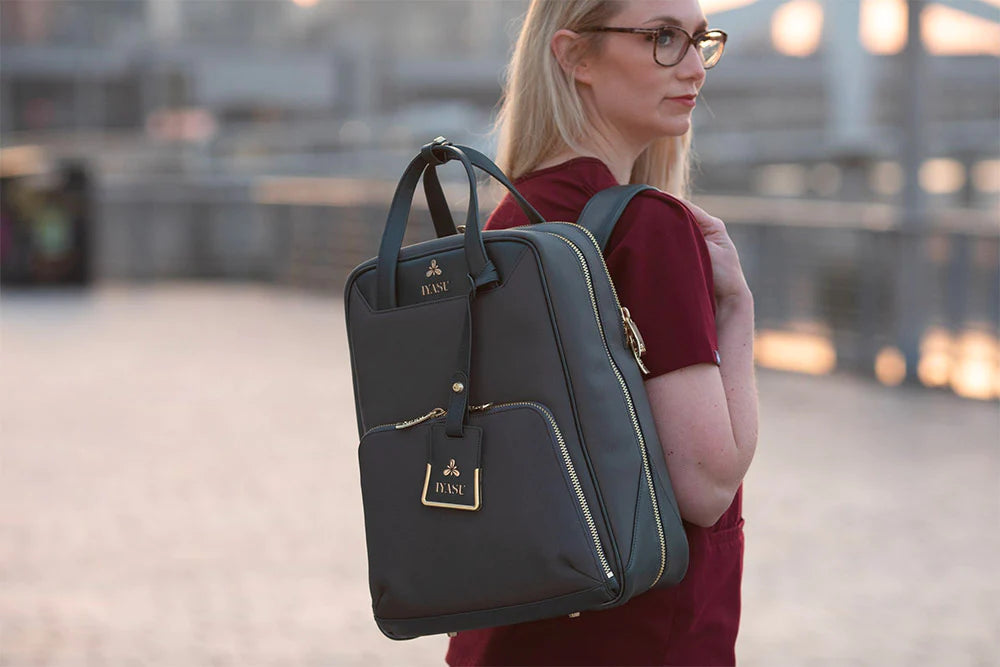 A woman wearing glasses is holding a black, eco-friendly IYASU Elsie Medical Bag.