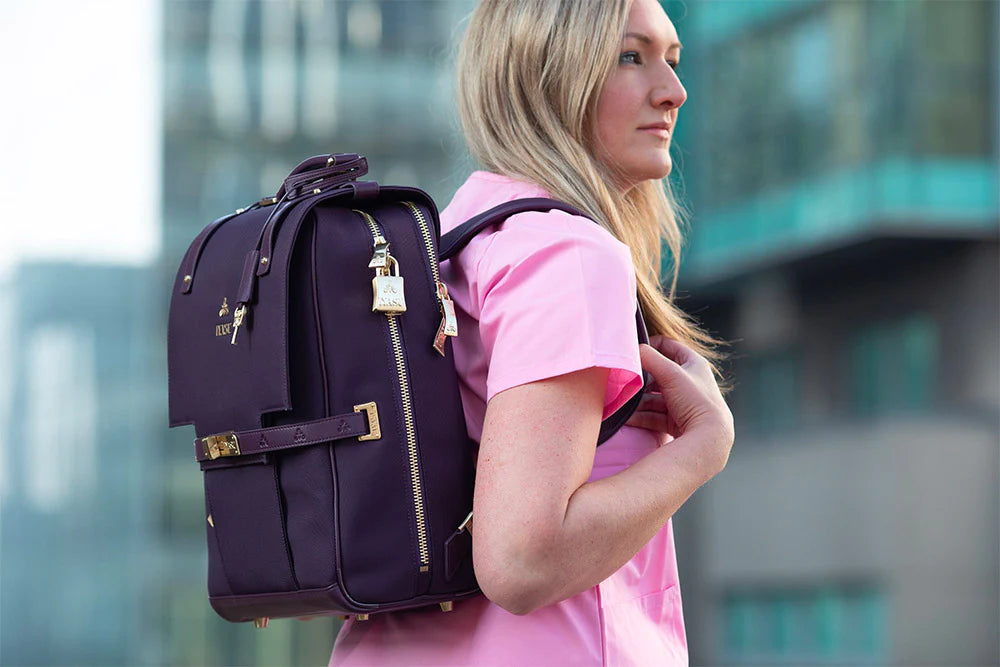 A woman in a pink shirt is carrying a purple eco-friendly IYASU backpack.
