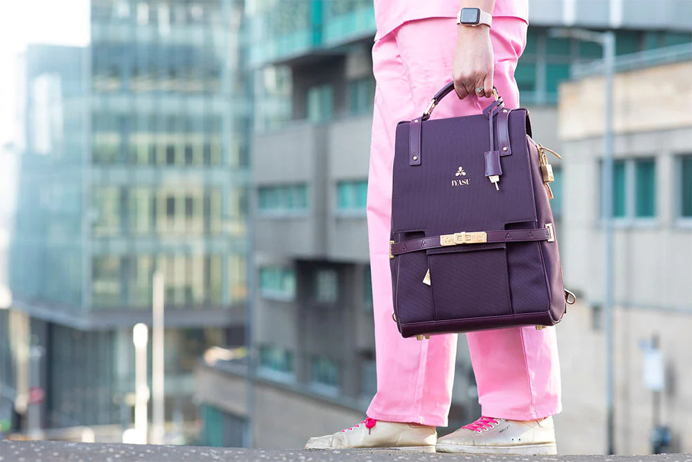 A woman wearing pink pants and pink shoes holding an eco-friendly IYASU Patricia Medical Bag in black.
