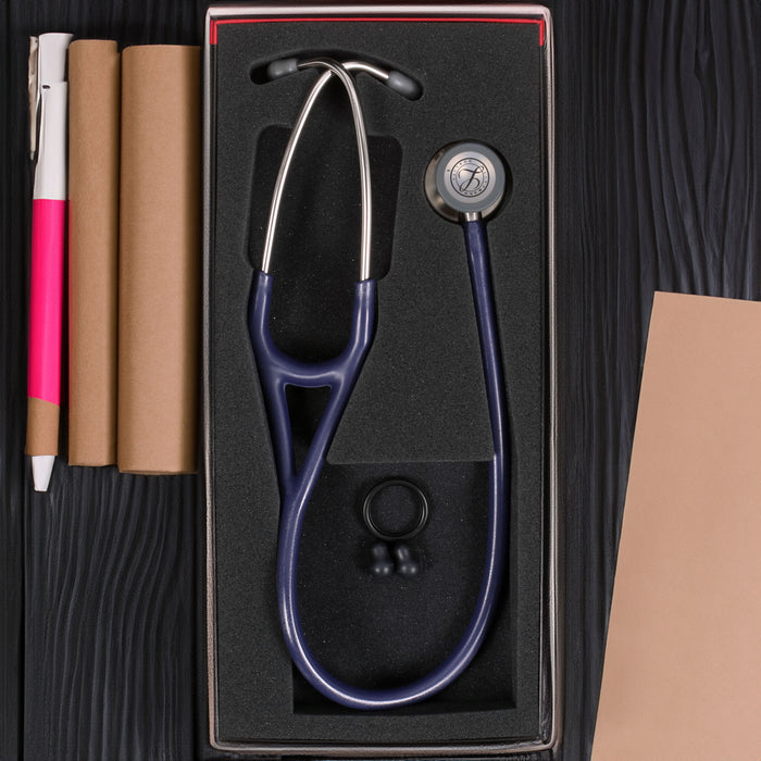 A 3M™ Littmann® Cardiology IV Diagnostic Stethoscope in Satin Midnight Blue Tube 6187C and medical supplies arranged neatly in a box on a black wooden background.